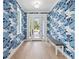 Stylish foyer with unique wallpaper, hardwood floors, a bench, and a glass front door at 1647 Siesta Dr, Sarasota, FL 34239