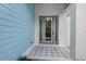 Eye-catching front door with patterned tile and sidelights, complemented by the home's blue siding at 1647 Siesta Dr, Sarasota, FL 34239