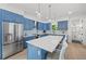 A kitchen with a large island with bar seating, blue cabinets, and stainless-steel appliances at 1647 Siesta Dr, Sarasota, FL 34239