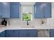 Stylish kitchen with a white countertop, blue cabinets, a modern faucet, and mosaic tile backsplash at 1647 Siesta Dr, Sarasota, FL 34239