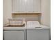 Bright laundry room with a white washer, dryer, overhead cabinets, and laundry basket at 17626 Gawthrop Dr # 305, Bradenton, FL 34211