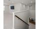 Bright hallway with white walls, tile floors, and wood railing staircase leading to downstairs at 17966 Grand Prosperity Dr, Venice, FL 34293