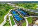 Aerial view of the community tennis and bocce ball courts surrounded by lush landscaping, and palm trees at 17966 Grand Prosperity Dr, Venice, FL 34293