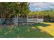 View of home's backyard with a fenced horse stable/pen, mature trees, and well-maintained lawn at 2070 59Th St, Sarasota, FL 34243
