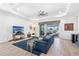 Spacious living room with large blue couch, tile floors, modern fan, and access to the pool at 25325 Longmeadow Dr, Punta Gorda, FL 33955