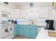 Bright kitchen featuring white cabinets, modern appliances, and stylish blue bottom cabinets at 3000 Gulf Dr # 3, Holmes Beach, FL 34217