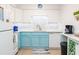 Well-lit kitchen featuring modern white appliances, ample counter space, and stylish blue bottom cabinets at 3000 Gulf Dr # 3, Holmes Beach, FL 34217