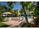 Community pool with lounge chairs, tables, and umbrellas surrounded by lush tropical plants and greenery at 3000 Gulf Dr # 3, Holmes Beach, FL 34217