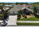 Aerial view of a home showcasing its landscaped yard, two-car garage, and proximity to neighboring houses at 457 Lake Of The Woods Dr, Venice, FL 34293