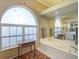Bright bathroom features a large bathtub, vanity, and arched window for natural light at 457 Lake Of The Woods Dr, Venice, FL 34293