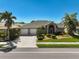 Beautifully landscaped home with a well-manicured lawn, palm trees, and a two-car garage at 457 Lake Of The Woods Dr, Venice, FL 34293