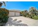 Attractive single-story home with a spacious driveway, tropical landscaping, and a two-car garage at 457 Lake Of The Woods Dr, Venice, FL 34293