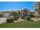 Charming single-story home featuring a well-manicured lawn, tropical plants and a covered entryway with decorative accents at 457 Lake Of The Woods Dr, Venice, FL 34293