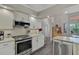 Modern kitchen with white cabinets, stainless steel appliances, and granite countertops at 457 Lake Of The Woods Dr, Venice, FL 34293