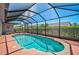 A screened-in swimming pool featuring clear blue water, a brick-lined border, and an outdoor seating area at 457 Lake Of The Woods Dr, Venice, FL 34293