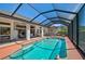 A screened in in-ground pool is surrounded by lounge seating and a covered outdoor living area at 457 Lake Of The Woods Dr, Venice, FL 34293