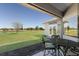 Covered lanai with a table and chairs, overlooking the lush green lawn and water views at 4606 Lake Fox Pl, Parrish, FL 34219