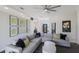 Bright living room featuring a gray sectional sofa, modern ceiling fan, and dark wood flooring at 4606 Lake Fox Pl, Parrish, FL 34219