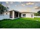 View of the back exterior featuring a white fence, a screened in patio, and a large green lawn at 4706 Cayo Costa Pl, Bradenton, FL 34203