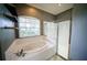Bright bathroom with a soaking tub under a window and a glass-enclosed shower at 4706 Cayo Costa Pl, Bradenton, FL 34203