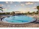 Community outdoor pool featuring lounge chairs, palm trees and a pool house at sunset at 4706 Cayo Costa Pl, Bradenton, FL 34203