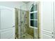 Shower with mosaic tiled walls, rain shower head, grab bar and a window at 5223 Chase Oaks Dr, Sarasota, FL 34241