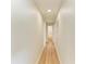Clean hallway featuring light walls, wood floors, and a view leading to a bathroom at the end at 5311 San Jose Dr, Sarasota, FL 34235