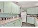 Bright kitchen featuring mint green cabinets, white appliances, and ample counter space at 709 Riverview Cir, North Port, FL 34287