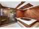 Unique bathroom with jetted tub, walk-in shower, wood paneling, and a skylight at 8036 Conservatory Cir, Sarasota, FL 34243