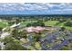 Aerial view of a clubhouse featuring ample parking, lush landscaping, and a manicured golf course at 8036 Conservatory Cir, Sarasota, FL 34243