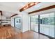 Open living room features hardwood floors, exposed beams, and sliding glass doors leading to a sunroom at 8036 Conservatory Cir, Sarasota, FL 34243