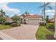Beige home with an expansive brick driveway, a two-car garage, and lush landscaping at 805 3Rd E St, Palmetto, FL 34221