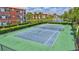 Well-maintained tennis court nestled within a community with colorful buildings, palm trees, and a pond at 8341 38Th Street E Cir # 303, Sarasota, FL 34243
