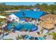 Aerial view showcasing a large pool with lush landscaping, waterfall features, tiki bar, and ample lounge seating under colorful umbrellas at 9902 284Th St E E St, Myakka City, FL 34251