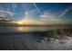 Sunset view over a sandy beach with sea grass, a calm ocean, and a vibrant sky at 11717 Blue Hill Trl, Lakewood Ranch, FL 34211