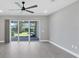 Living room showing gray plank flooring, ceiling fan, and sliding glass doors to the backyard at 11717 Blue Hill Trl, Lakewood Ranch, FL 34211