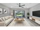 Bright living room features modern ceiling fan, sliding glass doors to backyard, and gray plank flooring at 11717 Blue Hill Trl, Lakewood Ranch, FL 34211