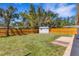 Spacious backyard features a lush lawn, wooden fence, storage shed, and mature trees, perfect for outdoor enjoyment at 1200 74Th N St, St Petersburg, FL 33710