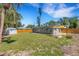 The wide backyard features a shed, lush lawn, wooden fence, fire pit, and mature trees at 1200 74Th N St, St Petersburg, FL 33710