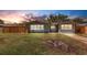 Charming single-story home featuring a well-maintained lawn and a wooden privacy fence at sunset at 1200 74Th N St, St Petersburg, FL 33710