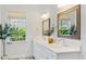 Bathroom featuring double sinks, white cabinets, quartz counters, and a view to the outside at 12307 Blue Hill Trl, Bradenton, FL 34211