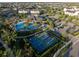 Aerial view showcasing a community pool, tennis courts, and gathering pavilion surrounded by palm trees and landscaping at 12307 Blue Hill Trl, Bradenton, FL 34211