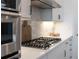 Stainless steel stovetop and range hood, with a white backsplash and countertops at 12307 Blue Hill Trl, Bradenton, FL 34211