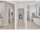 Hallway view of an elegant bathroom featuring marble flooring, a soaking tub, and separate toilet and shower areas at 13708 Red Rock Pl, Lakewood Ranch, FL 34202
