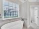 Elegant white soaking tub in the bathroom under a window, with tiled trim and a separate doorway at 13708 Red Rock Pl, Lakewood Ranch, FL 34202