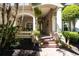 Charming home entryway featuring a brick path, columns, mature landscaping, and a decorative front door at 13955 Pine Woods E Ln, Sarasota, FL 34240