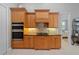 Kitchen featuring warm wood cabinets, modern appliances, and tile backsplash at 13955 Pine Woods E Ln, Sarasota, FL 34240