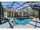 Large screened-in pool surrounded by ample seating, manicured landscaping, and covered patios at 13955 Pine Woods E Ln, Sarasota, FL 34240