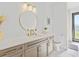 Bathroom featuring a stylish vanity with a round mirror, modern fixtures, and a neutral color palette at 16768 San Edmundo Rd, Punta Gorda, FL 33955