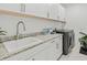 Well-equipped laundry room featuring white cabinets, a gray washer/dryer, and granite countertops at 16768 San Edmundo Rd, Punta Gorda, FL 33955